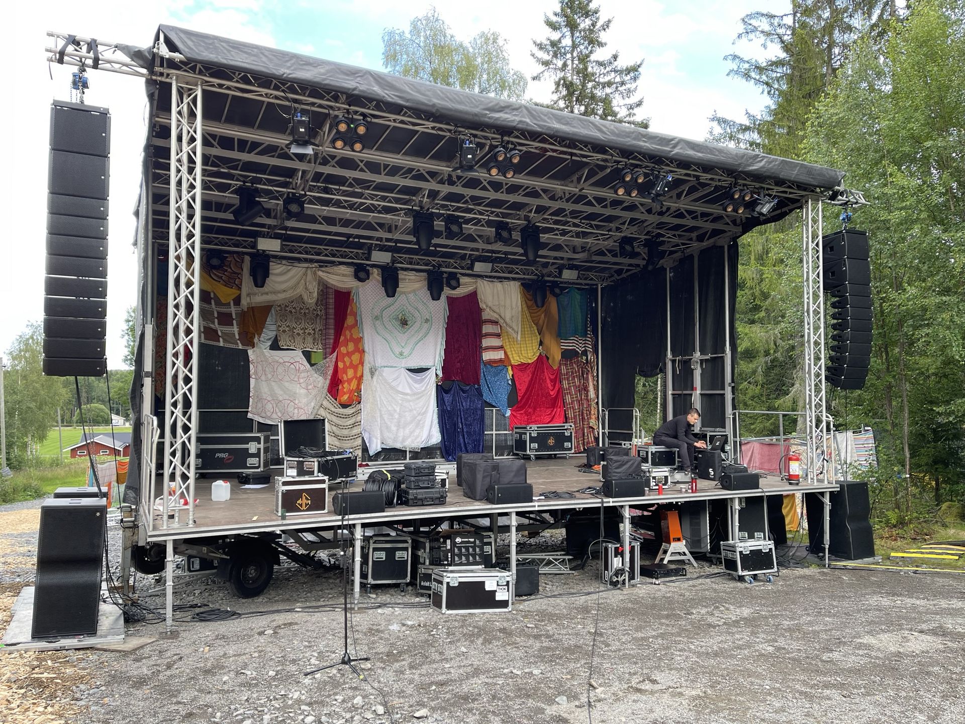 Utendørs festivalscene med lysrigg og hengende høyttalere